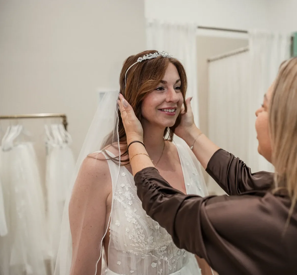 Ina steckt einer strahlenden Braut den Haarschmuck an