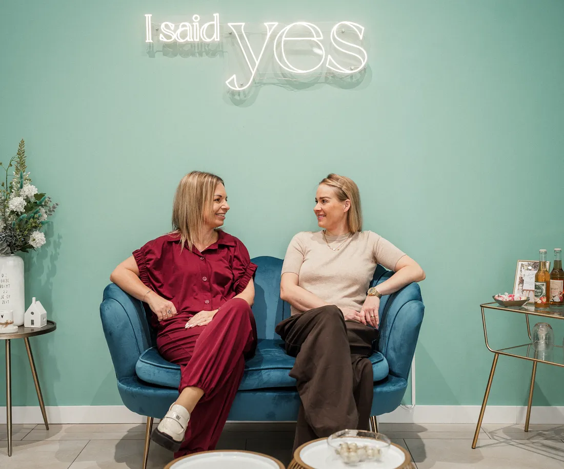 Gemütliche Sofaecke mit blauem Samtsofa vor dem Neonschriftzug von I said yes